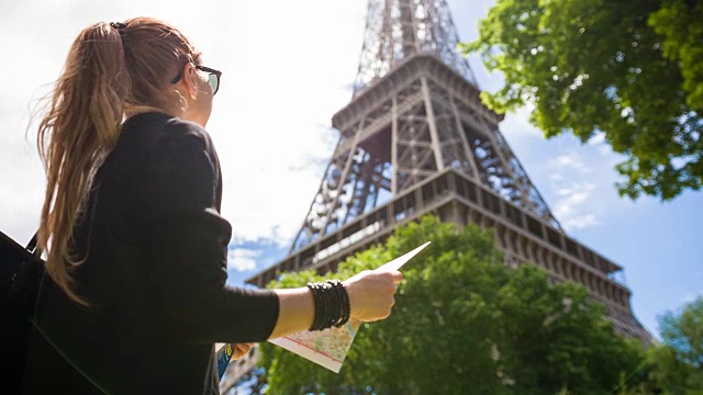 一个在阳光明媚的日子里走在巴黎街道上的女人正在欣赏埃菲尔铁塔视频素材