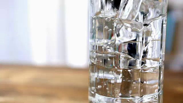 将水倒入加冰的透明玻璃杯中。视频素材