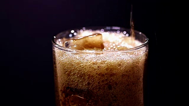 苏打水倒入加冰的透明玻璃杯中。视频素材