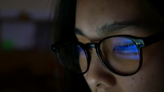 女人眼睛看着监视器，在晚上上网视频下载