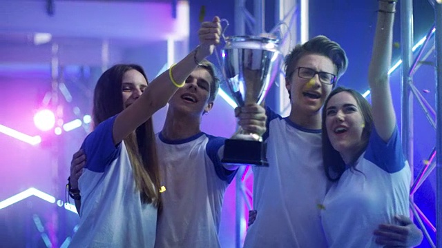 女孩和男孩在运动/电子竞技/电子游戏比赛中获胜，庆祝他们的胜利，举起奖杯。视频下载