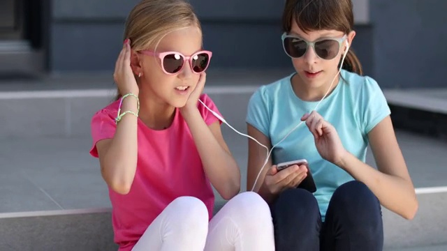 小女孩在智能手机上听音乐，唱歌视频下载