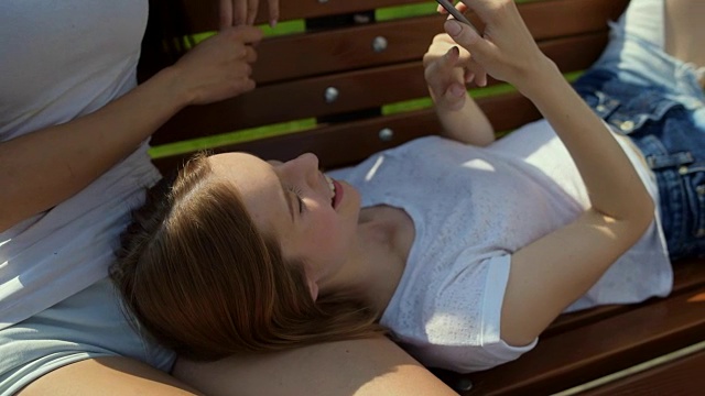 一个愉快的女孩躺在长凳上视频素材