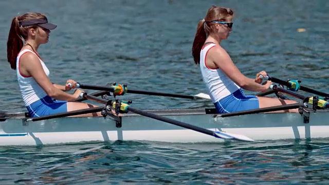 两名女运动员在阳光明媚的湖面上划桨视频素材