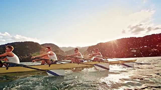 在陽光的背景下，男運動員在湖中推進四槳視頻素材