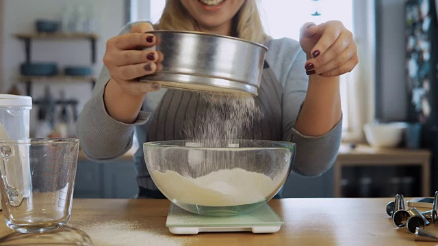 年轻美丽的女人用厨房秤，碗和筛面粉的特写视图视频下载