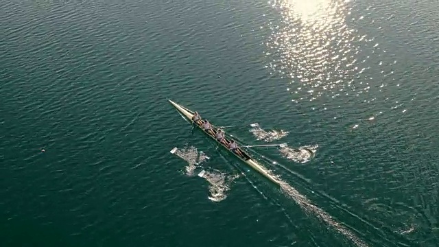 空中四名运动员在阳光下划船横渡湖面视频素材