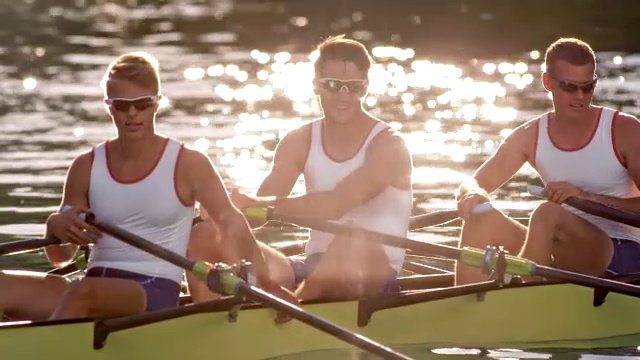 在阳光明媚的湖面上，男运动员在他们的四桨中休息视频素材