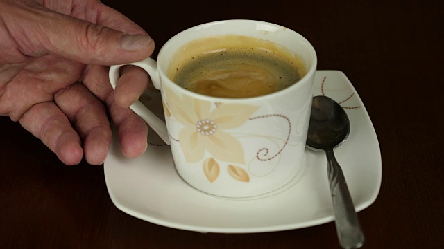 男性的手从茶碟上拿起咖啡杯。锁定。用泡沫咖啡。新鲜的咖啡。视频下载