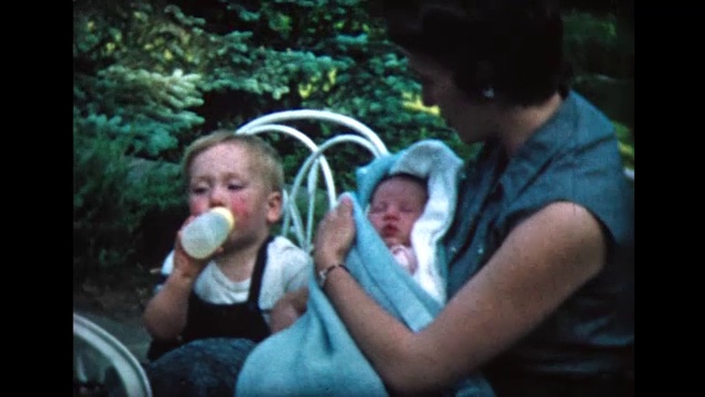 母亲抱着婴儿，小男孩摸着小妹妹的鼻子视频下载