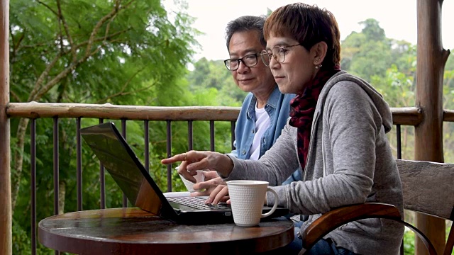 老夫妇在阳台上讨论和使用笔记本电脑视频下载