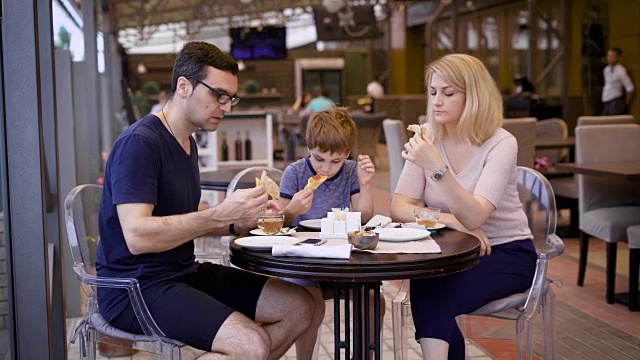 一个幸福的家庭在餐厅用餐，一对夫妇点了一份披萨，他们的小儿子很满意父母美味的选择视频下载