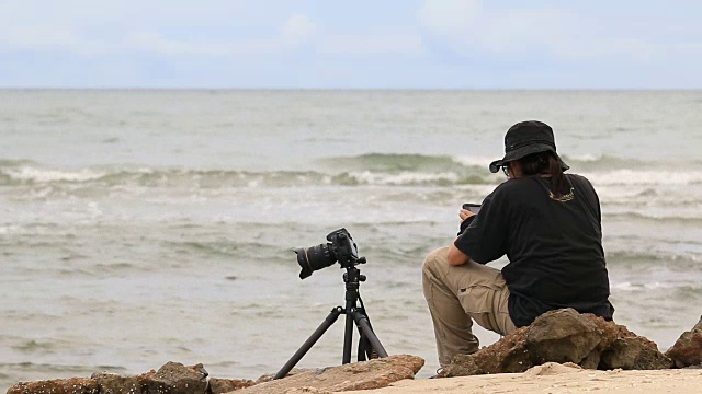 一个年轻人在户外的海滩上拍照视频下载