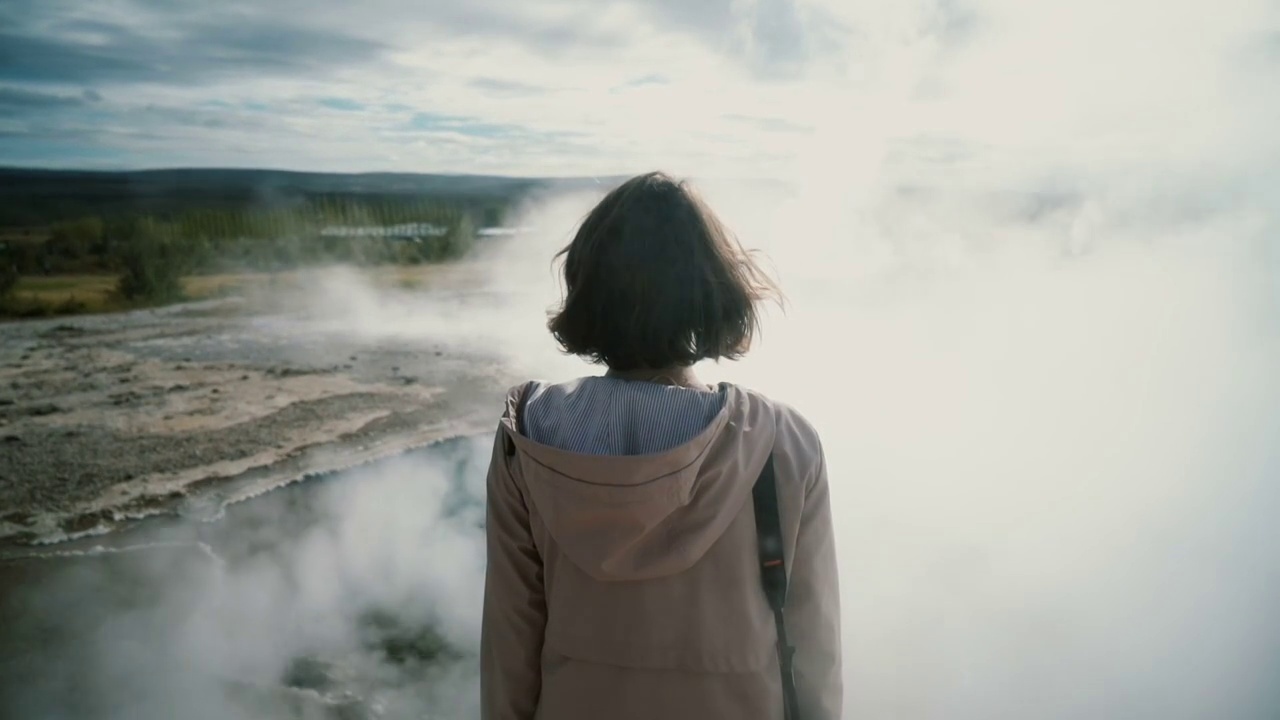 一个女人站在冰岛的间歇泉旁视频下载