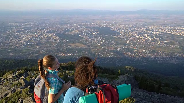 一对异族情侣在山顶上休息，聊天，指指点点，看着风景。视频下载