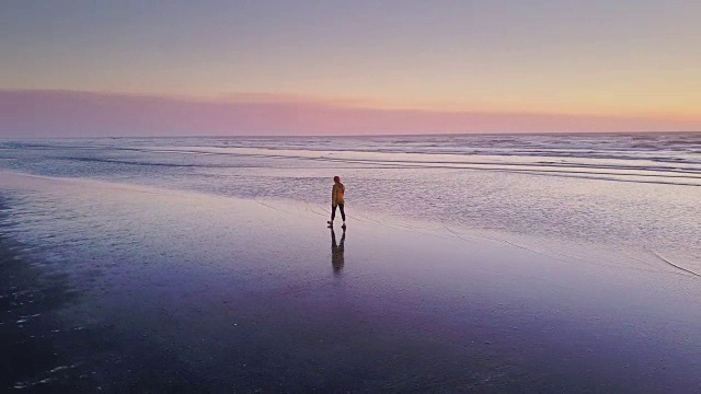 无人机射击-孤独的女人走在海滩上的日落视频下载