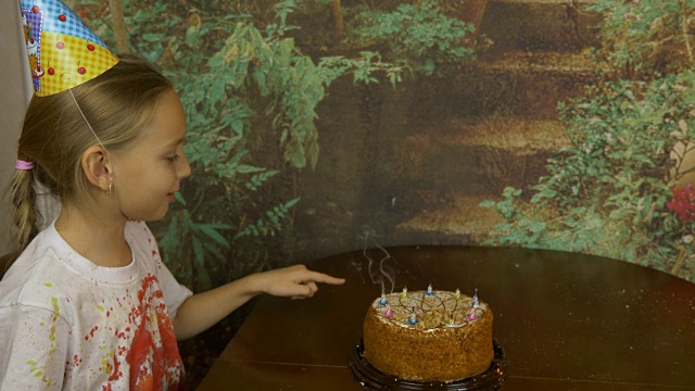 女儿和父亲一起庆祝生日。女孩把蛋糕上的蜡烛都熄灭了。烟从熄灭的蜡烛上飘过。女孩用手驱散了烟雾。视频下载