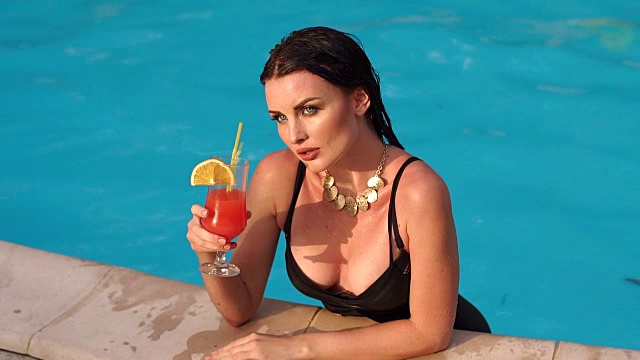 性感的黑发女子肖像与鸡尾酒在泳池。视频下载