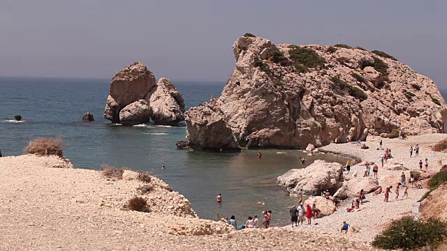 人们在塞浦路斯岛上的一个小沙滩上沐浴和晒太阳，这里是阿芙罗狄蒂的诞生地。礁石从海水中伸出来，地中海的美丽沙滩，岩石沙滩视频下载