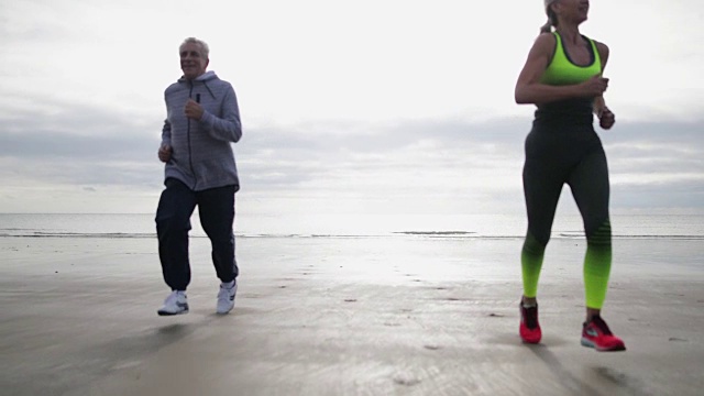一对老年夫妇在海滩上慢跑视频素材