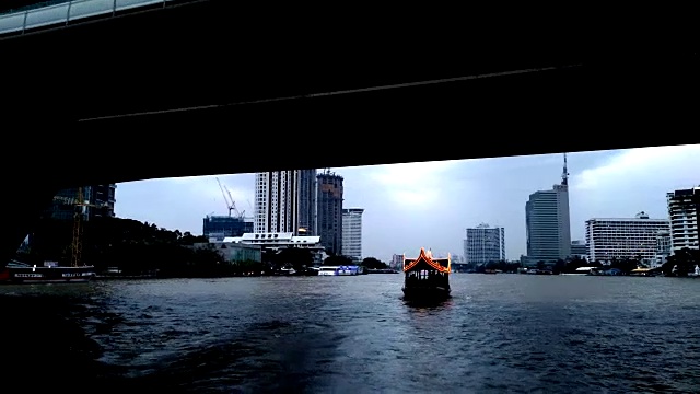一艘船在湄南河上行驶，湄南河穿过曼谷的心脏地带，位于布满豪华酒店和公寓的沙顿商业区。视频下载