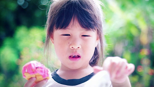 小女孩在吃美味的甜甜圈。视频素材