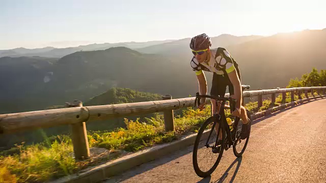 男运动员站在路上骑自行车上山视频下载