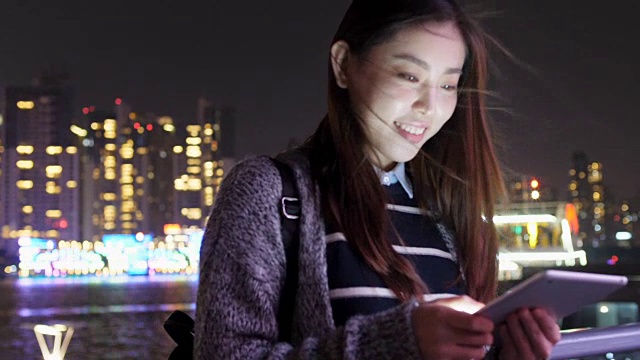 年轻的亚洲妇女在现代城市玩手机视频下载