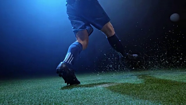 SLO MO足球运动员在晚上的竞技场上踢球视频下载