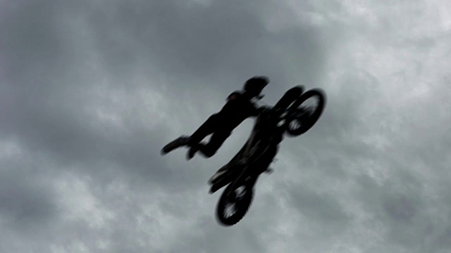 自由式摩托车越野赛FMX骑手慢动作跳跃剪影。七名勇敢的摩托车手一个接一个地在接近跳板后空翻的危险中跳跃视频下载