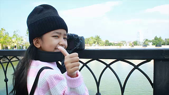 4K亚洲小女孩用拍摄相机拍照，用快乐竖起大拇指，假日旅行的概念视频下载