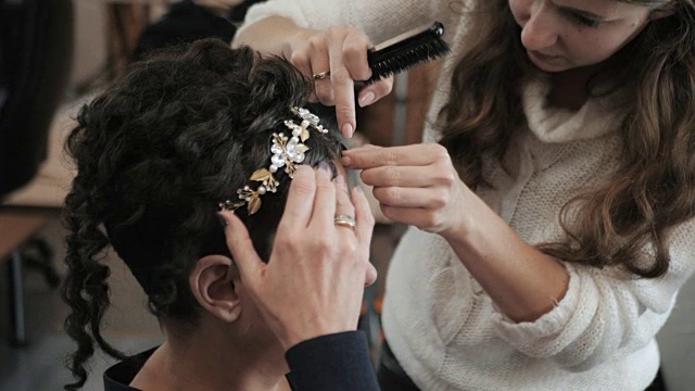 一个女人在美发沙龙做发型。造型师正在努力为一位中年妇女创造一种具有历史意义的造型。把头饰戴在头上。慢动作视频下载