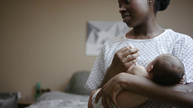 美丽年轻的非洲裔母亲穿着医院长袍，抱着她的混血女婴视频下载