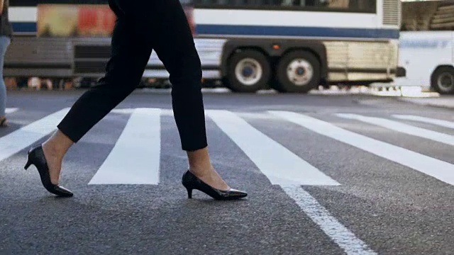 近距离观看年轻女商人穿着高跟鞋在繁忙的市中心过马路。慢动作视频素材