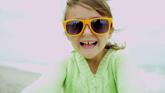 快乐的小白人女孩在户外海滩挥动相机视频下载