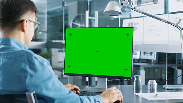 在個人電腦上工作的汽車工程師，電腦上有獨立的綠屏模型。他在明亮而現代的辦公室工作，墻上掛著汽車草圖。視頻素材
