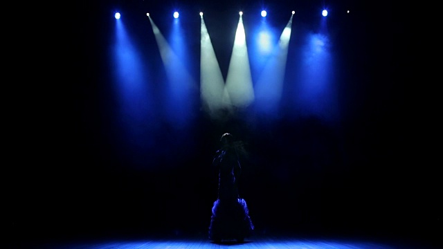 美丽的歌手在舞台上与蓝色的光。视频下载