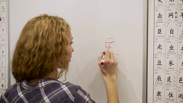 一名年轻女子用记号笔在白板上写象形文字视频素材