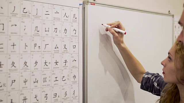 一个年轻人教一个年轻女子读和写中文视频素材