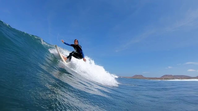 慢镜头:一个冲浪者在冲浪板上做了一个急转弯，溅到照相机上。视频购买