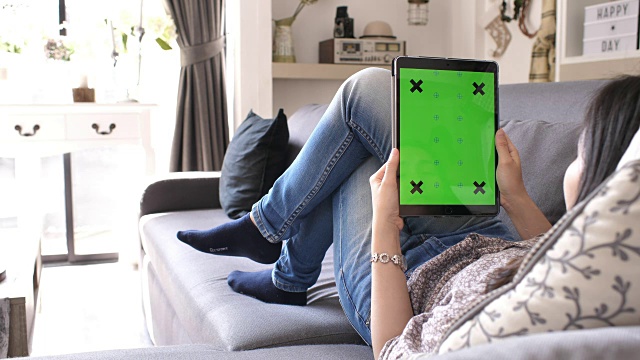 Cinemagraph年轻女子在家里拿着绿色屏幕的数字平板电脑视频下载
