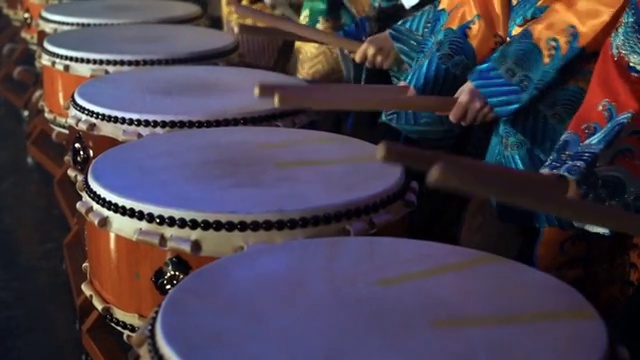 来自Taiko in - spirational亚洲鼓表演的鼓手身着亚洲传统服装在亚洲新年音乐会期间表演，近距离观看侧面的鼓。视频购买