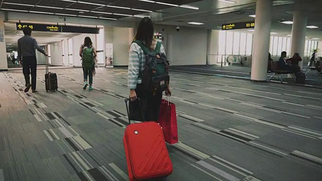 带着红色行李的女旅客走过机场航站楼视频素材