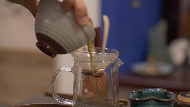 用手将沏好的绿茶倒入有滤纸的玻璃茶壶中视频素材