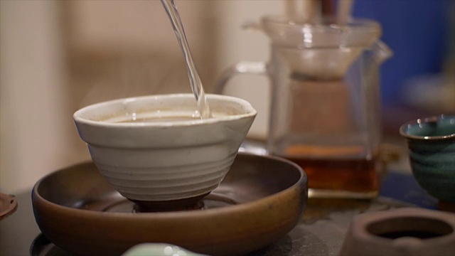 男用手将热水倒入装有绿茶的碗中。传统的茶道视频素材
