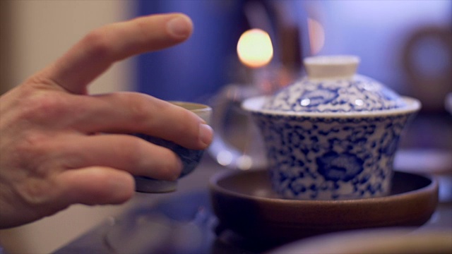 男性用手将热水倒入碗中冲泡茶叶。男子手拿茶杯视频素材