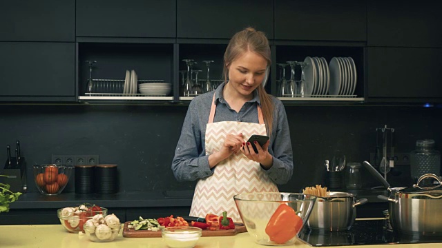 年轻女子在做饭时使用智能手机视频素材