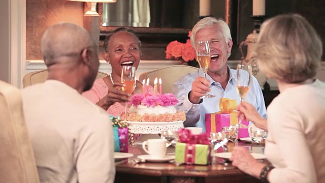 成熟的夫妇举杯互敬香槟，女人吹灭生日蛋糕上的蜡烛视频下载