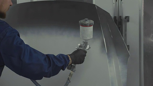 汽车油漆工在专用车棚的引擎盖上喷涂白色油漆视频下载