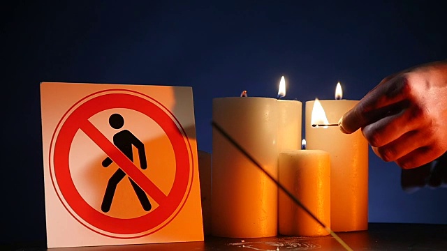 许多燃烧着的蜡烛挥舞着黄色的火焰，黑色背景上写着“禁止人们进入”。用来庆祝活动和闪电的又圆又粗的燃烧棍棒视频素材